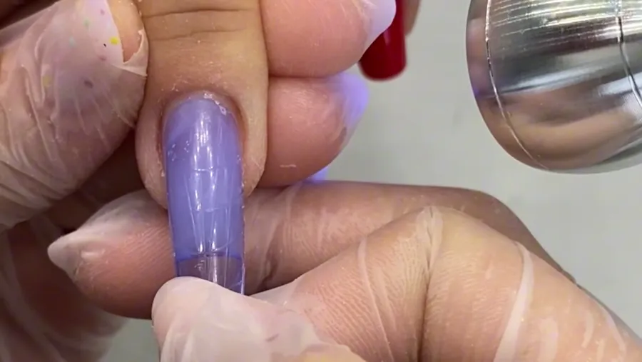 O molde lilás com gel encaixado na unha.